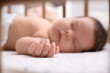 © New Africa - Cute little baby sleeping in crib at home, focus on hand. Bedtime