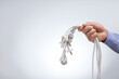 © Sergey - Hand holding many electrical plugs on a grey background with copy space. Energy saving concept.