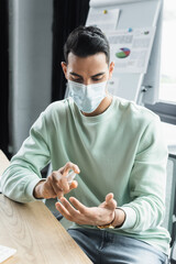 Wall Mural - Muslim businessman in medical mask using hand sanitizer in office