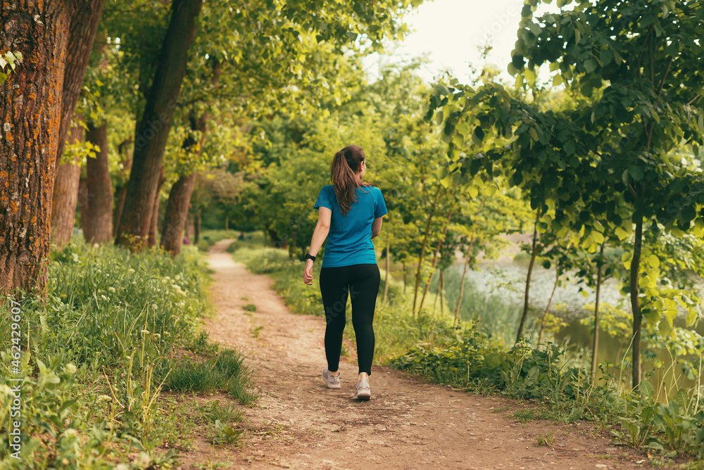 Active young woman is walking on a path in the forest on daytime. Stock ...
