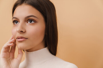 Wall Mural - Young brunette woman touching her face and looking aside