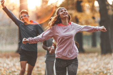 Red hair female in casual sport outfit jogging with her friends at city park.	
