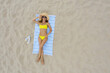 © New Africa - Woman sunbathing on beach towel at sandy coast, aerial view. Space for text