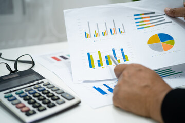 Asian accountant working and analyzing financial reports project accounting with chart graph and calculator in modern office, finance and business concept.