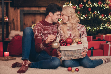 Sticker - Portrait of two attractive sweet tender dreamy married spouses sitting on carpet decorating fir tree newyear custom indoors