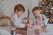 © Cavan Images - Cheerful cute children boys opening gifts under christmas tree.