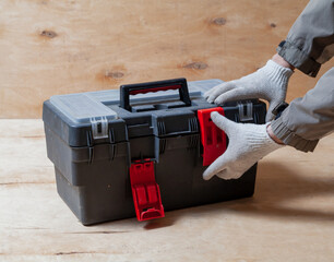 Hands open toolbox on wooden background