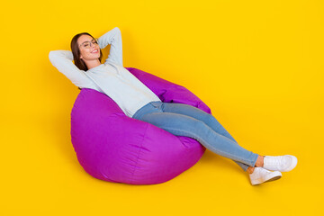 Poster - Full length photo of happy positive woman enjoy sit bean bad relax hands behind head isolated on yellow color background