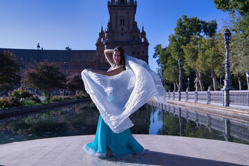 Wall Mural - Middle-aged Hispanic woman in turquoise dress with rhinestones, belly dancing with a white veil. Belly dance concept.