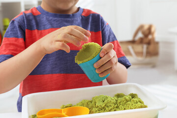 Sticker - Little boy playing with bright kinetic sand at table indoors, closeup