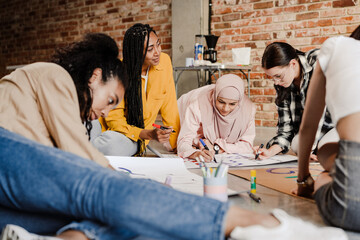 Multiracial young feminist women making posters during meeting