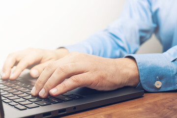 Male hands typing on a laptop keyboard, close-up view