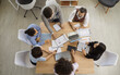 © Studio Romantic - Group of women and man working together. Young Businesspeople Discussing Data In Meeting Room. Group Of Businesspeople Working On Laptop. Business people group meeting shot from top view in office .