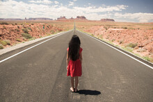 Girl in red dress standing on the highway  road near monument valley arizona usa