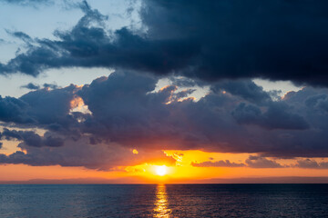 Wall Mural - Stunning dramatic, cloudy sunrise with a bright sun rising over a calm water. Natural background, Sardinia, Italy.