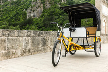 Empty Yellow Pedicab Rickshaw Bicycle On The Old Medieval Stone Bridge