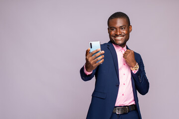 Wall Mural - young african businessman using his phone rejoicing