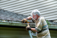 Man Cleans Out Gutters On His House