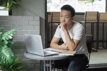 Wall Mural - Online studying concept the young man in simple white T-shirt being thoughtful and serious in front of the screen during the online class