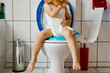 Closeup of cute little toddler baby girl child sitting on toilet wc seat. Potty training for small children. Unrecognizable face of child