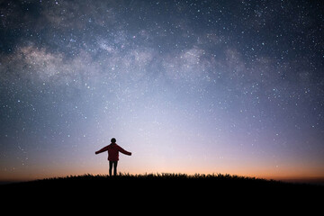 Wall Mural - Young traveler and backpacker standing and raise both arms watched the star and milky way alone on top of the mountain. He enjoyed traveling and was successful when he reached the summit.