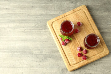 Wall Mural - Glass jars of raspberry jam with ingredients on wooden board