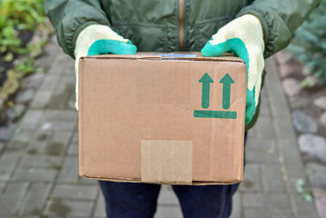 Delivery man is holding a parcel with a fragile symbol on a cardboard box. Delivery of the parcel courier service to your home. Sending fragile items by courier..