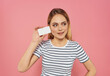 © SHOTPRIME STUDIO - blonde woman in a striped T-shirt with a business card in hand pink background