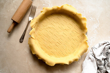 Tart dough or shortcrust pastry, in ceramic tart pan. Baking at home.