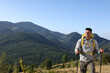 © New Africa - Tourist with backpack and trekking poles hiking through mountains, space for text