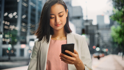 Sticker - Portrait of an Attractive Japanese Female Wearing Smart Casual Clothes and Using Smartphone on the Urban Street. Manager in Big City Connecting with People Online, Messaging and Browsing Internet.