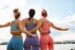 © Georgii - Happy women in fitness clothes relaxing and having fun in the park by the river. Fitness, sport, friendship and healthy lifestyle concept . Group of happy people exercising