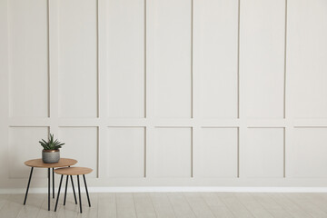 Sticker - Tables with potted houseplant near empty wall indoors. Space for design