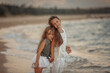 Two sisters playing on the shore of the sea at summer evening