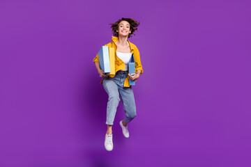 Sticker - Photo of funny pretty young woman dressed yellow shirt smiling jumping holding documents isolated purple color background