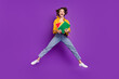 Full length body size view of attractive amazed cheery girl jumping holding book isolated over bright violet purple color background