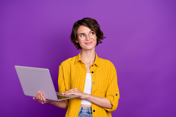 Portrait of attractive dreamy minded cheery girl holding using laptop startup isolated over bright violet purple color background