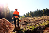 Fototapeta Natura - Professioneller Waldarbeiter, Holzfäller mit Arbeitsschutzkleidung und Kettensäge bei der Arbeit im Wald