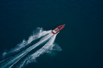 Diagonal boat movement on blue water top view. Red speed boat fast movement on the water top view. Travel - image. Top view of a red fast boat.