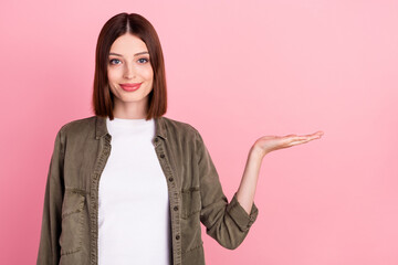 Wall Mural - Photo of optimistic bob hairdo millennial lady hold empty space wear khaki shirt isolated on pink color background