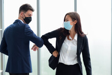2 Caucasian Business People Wearing Masks And Greet Each Other With Their Elbows Touching Each Other. Instead Of Touching With Hands To Reduce The Spread Of Corona Virus Or Covid-19 In The Workplace.