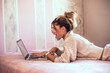 © Aitor Carrera Port√©/Westend61 - Surprised young woman lying on bed using laptop