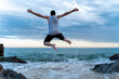 © VITTA GALLERY/Westend61 - Back view of young man jumping in the air at seafront