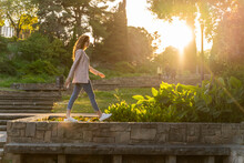 Young Redheaded Woman Walking On A Wall In A Park