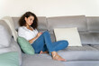 © VITTA GALLERY/Westend61 - Young woman taking notes on couch at home
