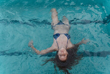 Portrait Of Young Woman Floating On Water In Swimming Pool