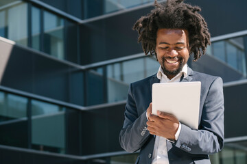 Smiling businessman using tablet outside office