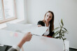 © Hernandez and Sorokina/Westend61 - Two young women working at desk in office handing over paper