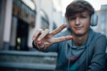 Portrait Of Teenager With Headphones Showing Victory Sign