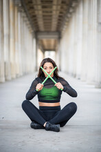 Young Woman Sitting On The Ground Holding Pound Exercise Sticks